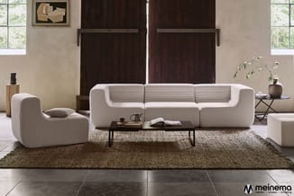 Beige modulaire zitgroep met loungestoel, driezits bank en poef op naturelkleurig tapijt in minimalistische woonruimte met do