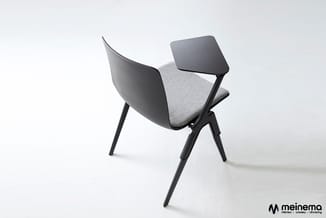 Moderne stoel met zwart metalen frame, grijze gestoffeerde zitting en gebogen zwarte kunststof rug en tafelblad.