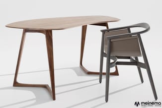 Houten eettafel met afgeronde blad en zwarte houten stoel met armsteunen in minimalistisch design.