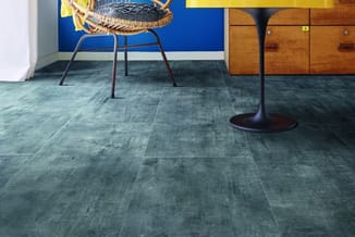 Moderne kantoorruimte met grijsblauwe tegelvloer, gevlochten stoel met metalen poten, houten kastenwand en blauwe muurpanelen