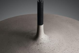 Betonnen tafelblad met geïntegreerde zwarte paal, detail van materiaal en textuur.