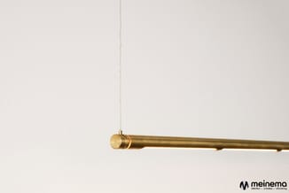 Gouden hangende stang tegen witte wand, minimalistisch design met ketting ophanging