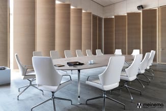 Moderne vergaderruimte met ovale tafel, witte kantoorstoelen op wielen, houten wandpanelen en geïntegreerde verlichting.