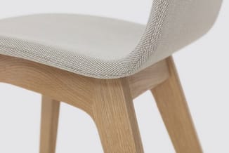 Moderne stoel met licht grijs mesh-zitting, houten frame in natuurlijk hout, gedeeltelijk zichtbaar van opzij.