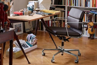 Kantoorruimte met houten bureau, zwarte bureaustoel met chromen frame en wieltjes, boekenkasten, houten speelgoed en document