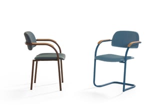 Twee stoelen met armleuningen: links bruin frame met blauwgrijs kussen, rechts blauw frame met blauw kussen.