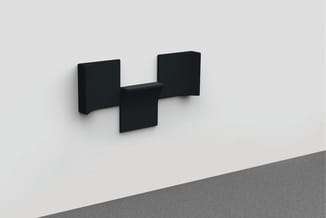 Zwarte akoestische wandpanelen in T-vorm geplaatst tegen lichte muur.