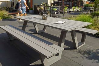 Outdoor picknickset met witte en donkergrijze picknicktafel en bijbehorende banken op terrein met groenvoorziening.