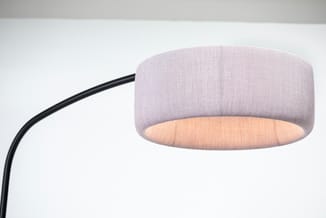 Detail van de lichtroze stoffen kap van de BuzziJet vloerlamp, met warme verlichting aan de onderzijde en een zwart gebogen frame.