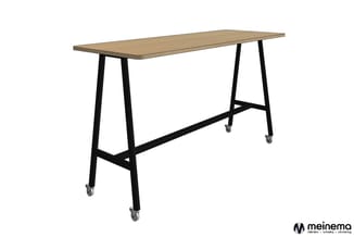 Hoge tafel met licht houten blad en zwart metalen onderstel op wielen, geschikt voor staand werken of vergaderingen.
