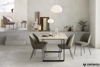 Moderne vergaderruimte met lichte houten tafel, vier grijsgroene stoelen met metalen poten, twee witte hanglampuitvoeringen,