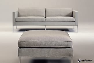 Grijze stoffen lounge set: tweepersoonsbank en voetenbankje met metalen poten op neutrale achtergrond.