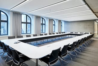 Moderne vergaderruimte met lange U-vormige vergadertafel in wit en zwart, zwarte kantelstoelen, grote ramen met grijze gordij