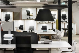 Modern kantoor met witte bureaus, zwarte bureaustoelen, houten vergadertafel met witte stoelen, zwarte hangende lampen en wit