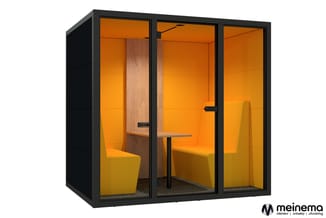 Moderne belcel met zwart frame, oranje wanden, houten scheidingswand, gele stoelen en kleine tafel. Gesloten werkplek voor co