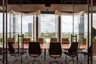 Moderne vergaderkamer met houten tafel, cognackleurige ergonomische stoelen, glazen wanden en houten lamellen aan plafond. Ui