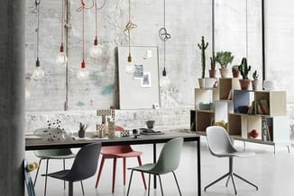 Modern kantoor met zwarte werkta­fel, gekleurde stoelen (zwart, rood, groen, wit), houten kastensysteem met cactussen, hangla