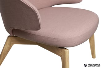 Roze stofbeklede loungestoel met afgeronde zitting en gebogen rugkuil, houten poten in natuurlijke houtkleur, detail van zijk