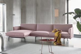 Roze hoekbank met chaise longue en zwarte metalen poten in moderne betonnen kantoorruimte met rood bijzettafeltje.