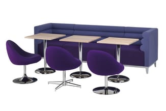 Loungehoek met donkerblauwe bank, drie paarse kuipstoelen met zwart voetstuk en drie houten tafeltjes met metalen onderstel.