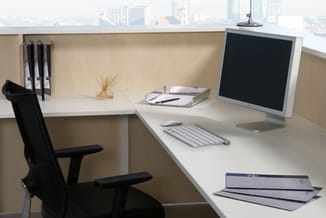 Moderne kantoorkamer met witte hoekbureau, zwarte ergonomische stoel, monitor, toetsenbord, notitieblokken en oranje bureauac