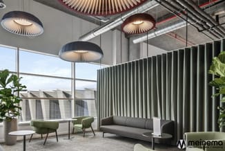 Modern kantoor met groene stoelen, grijze bank, verticale grijsgroene gordijnen, hangende plafondlampen en grote ramen met st