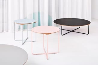 Drie ronde bijzettafels in verschillende kleuren: lichtblauw, roze en zwart, met metalen frames in een heldere interieurruimt
