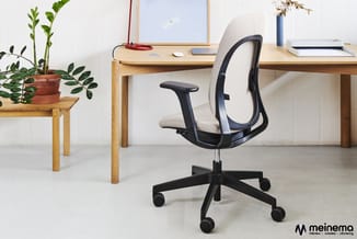 Kantoorwerkplek met houten bureau, zwarte ergonomische bureaustoel met beige zitting, houten plantentafeltje met groene plant
