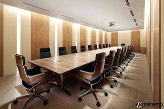 Moderne vergaderzaal met lange houten tafel, zwart-blauwe bureaustoelen met houten schalen, houten wandpanelen met geïntegree