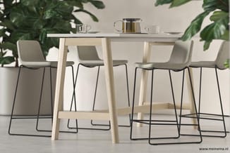 Houten bartafel met grijs-groene barstoelen met zwarte metalen poten, omgeven door groene planten in minimalistische kantoori
