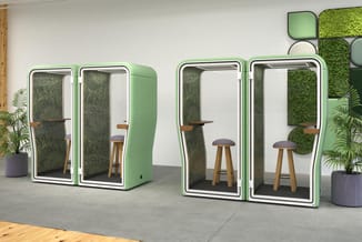 Groene akoestische belcellen met witte rand en glazen deuren in kantoor, voorzien van houten barkrukken en grijze akoestische