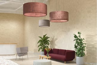 Moderne kantoorlobby met drie hangende cilindervormige lampen in rood en grijs, bordeauxrode sofa, grijze stoel, witte ronde