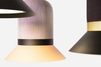 Hangende lamp met grijze stofkap, zwarte metalen band en geel-crème gekleurde kunststof kap.