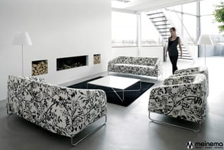 Moderne loungeset met twee fauteuils en een bank met wit-zwart bloemenpatroon, rond lage tafel, open kantoorruimte met raam e
