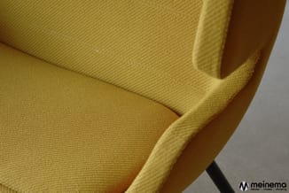 Gele stofbeklede stoel met armsteun, details van zitting en rugleuning in close-up weergegeven.