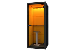 Zwarte akoestische belcel met oranje binnenwanden, voorzien van LED-verlichting, tafel en stoel.