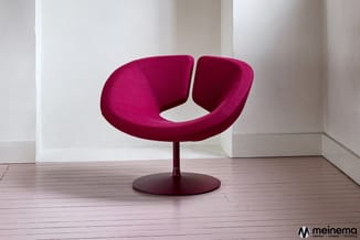 Fuchsia-roze draaibare fauteuilop ronde voet in minimalistische witte ruimte met houten vloer.