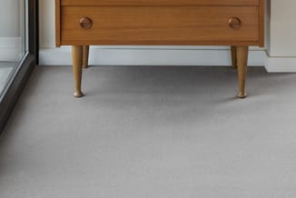 Houten retro dressoir met tapered poten op grijze tapijttegels in moderne kantoorruimte.