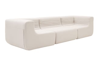 Modulaire bank in lichtbeige stof met afgeronde vormen, opgebouwd uit meerdere blokken, tegen witte achtergrond.