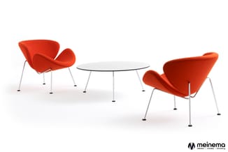 Twee rode stoelen met organische vormen rond een ronde witte tafel met chromen poten op witte achtergrond.