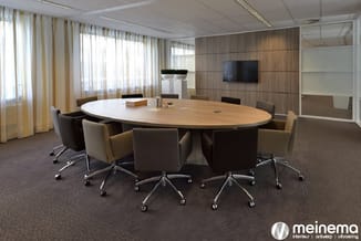 Moderne vergaderruimte met ovale houten tafel, bruine en beige stoelen op wielen, houten wandbekleding, TV-scherm, grote rame