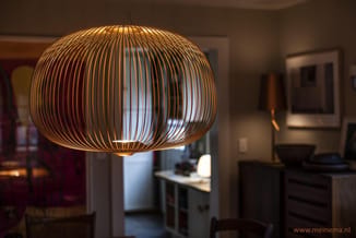 Gouden hanglamp met ronde, ovale vorm gemaakt van dunne metalen strippen in moderne kantoorruimte.