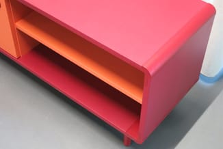 Roze en oranje kunststof kastje met open vakken, staand op grijze vloer.