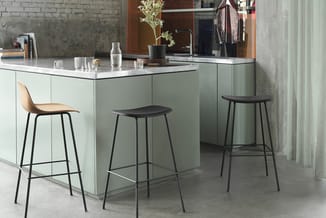 Moderne keukeneiland met mintgroene kastfront, wit werkblad, drie zwarte barkrukken en ingebouwde wastafel in minimalistisch