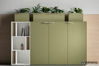 Groen-grijze kastencombinatie met witte open vakken, boeken en decoratie, plantenbakken bovenop, tegen lichte muur.