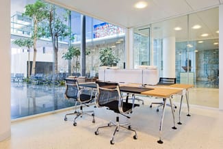 Modern kantoor met houten vergadertafel, zwarte bureaustoelen op wielen, witte receptie, grote ramen met uitzicht, potplanten