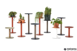 Collectie plantentafels in verschillende hoogten en kleuren (rood, bruin, grijs, wit) met ronde bladen, voorzien van potplant