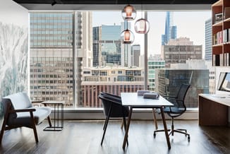 Modern kantoor op hoog niveau met witte werkstafel, zwarte bureaustoel, houten loungestoel, hangende glazen lampen en uitzich