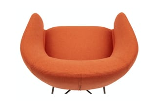 Oranje stoffen fauteuil met hoge, afgeronde oren en zwarte metalen poten, frontaal gefotografeerd.