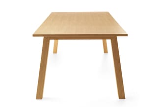 Houten vergadertafel met trapeziumvormig blad en vier rechte poten in licht eikenhout.